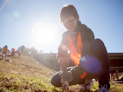 A student planting flowers on the side of a highway during the MLK day of Service.